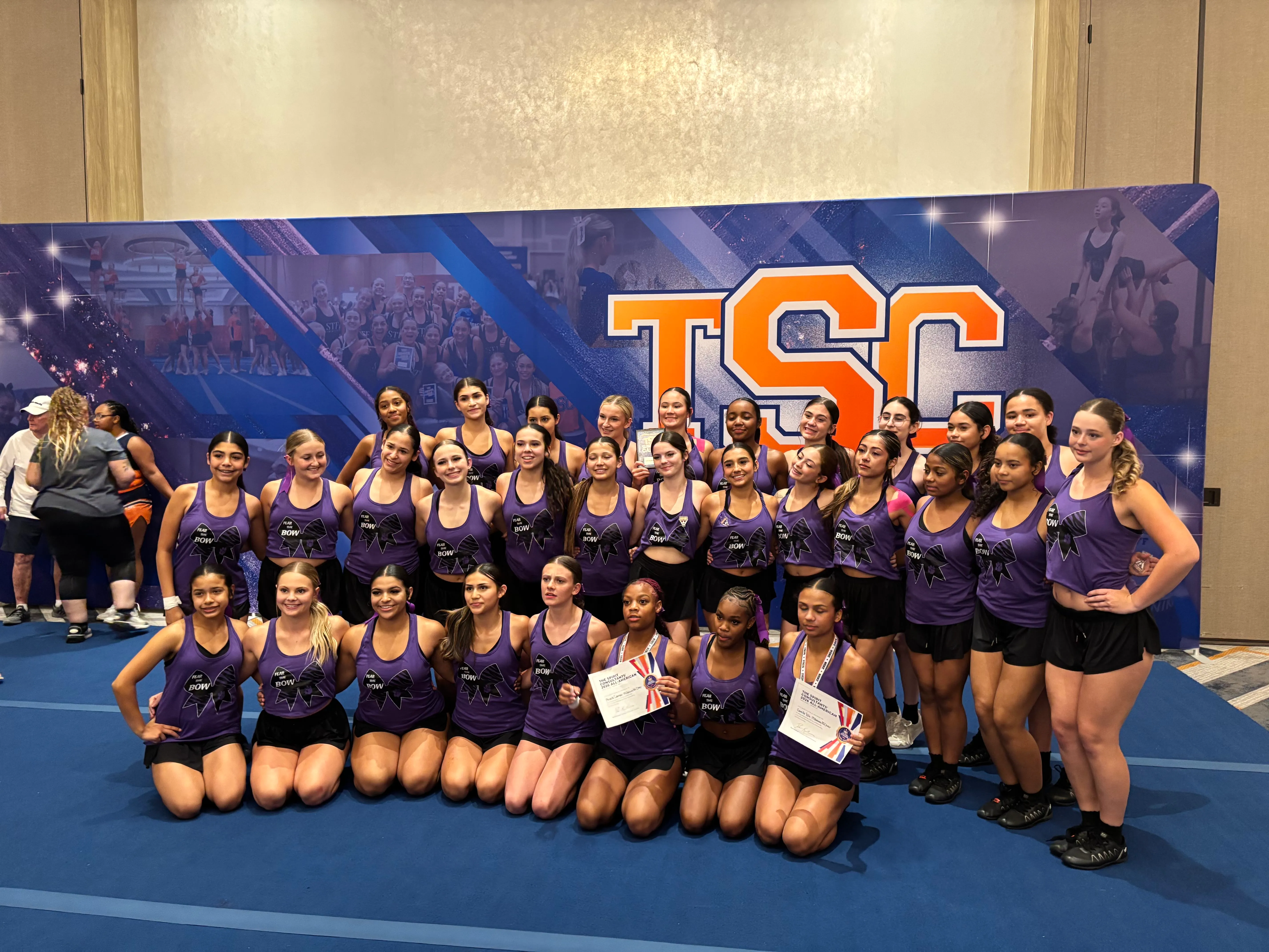 Millennium Tigers cheer team posing together in front of the TSC banner at Summer Camp